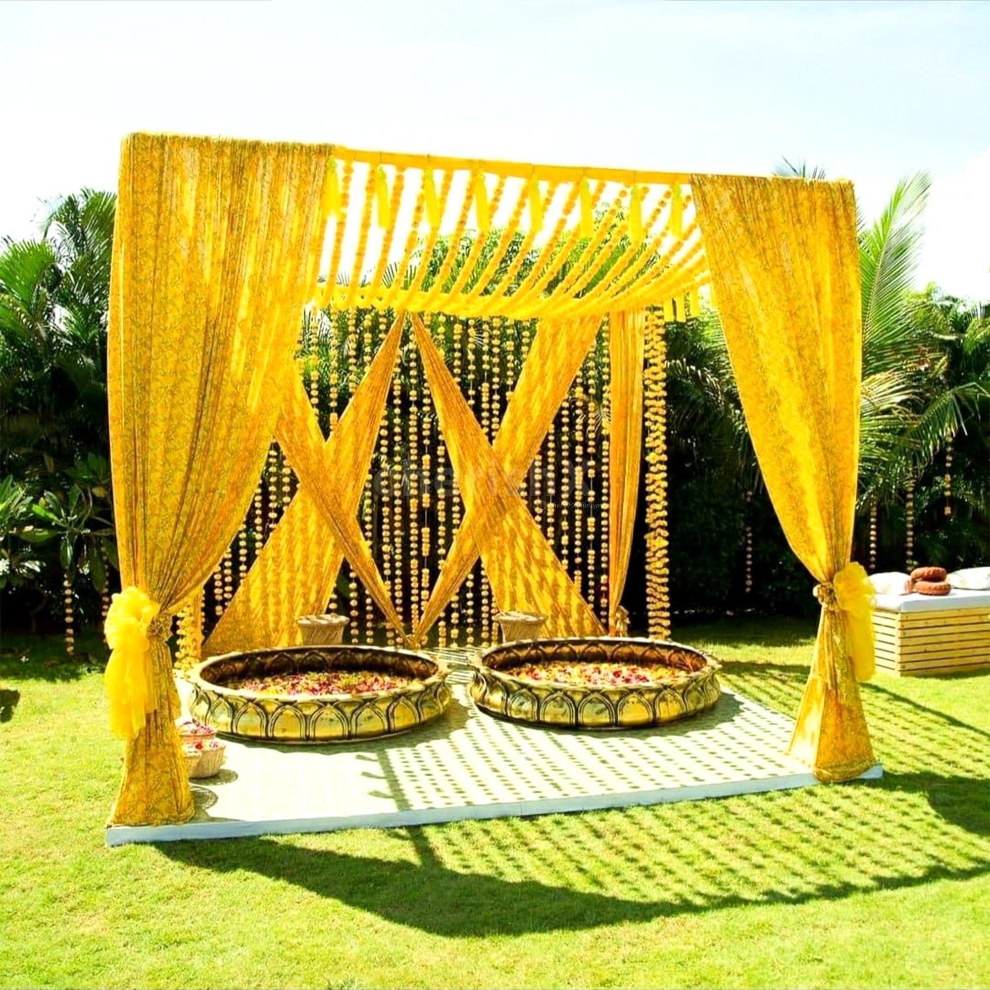 Regal yellow mandap stands covered in soft floral garlands.