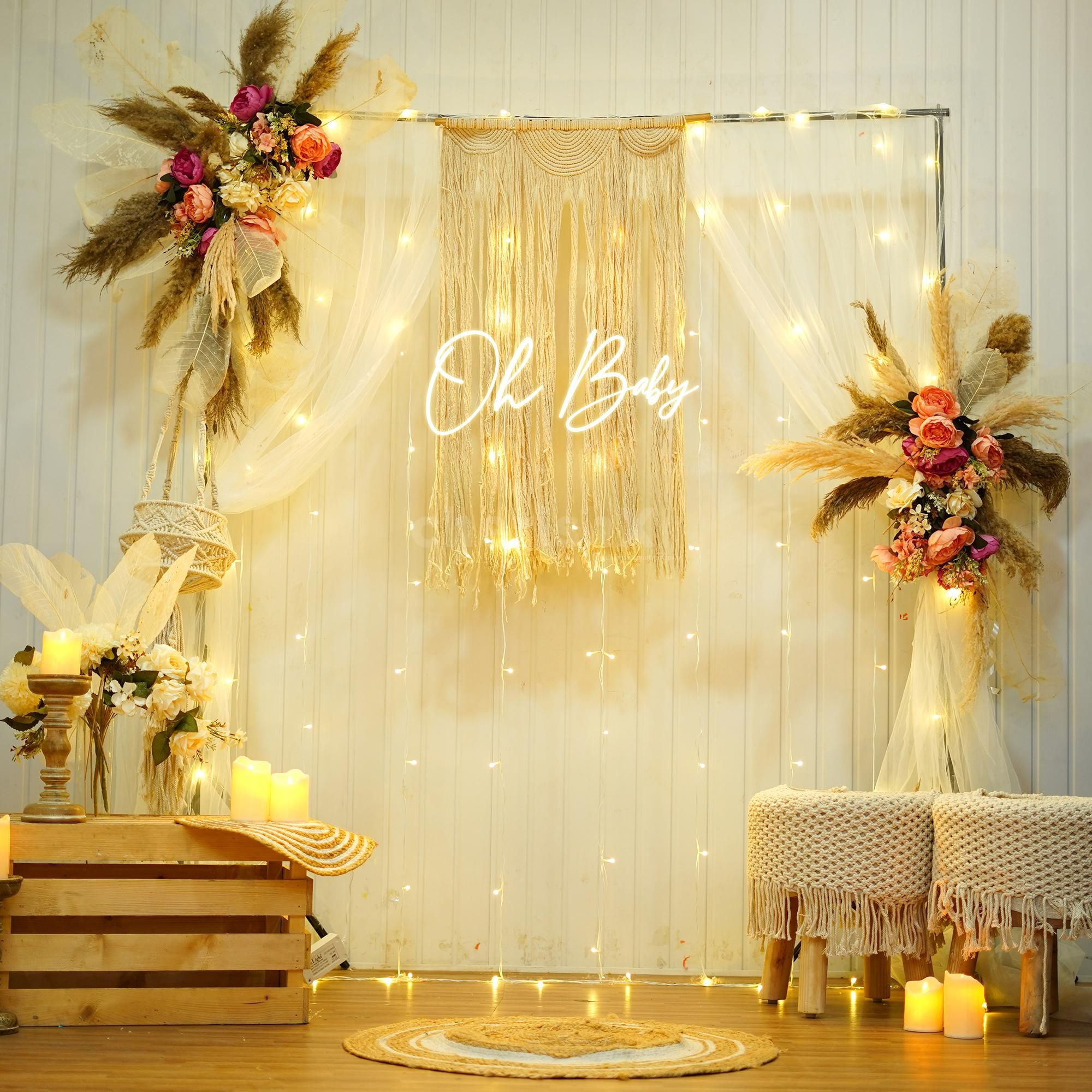 Pampas and boho drapery around a warm "Oh Baby" neon sign.